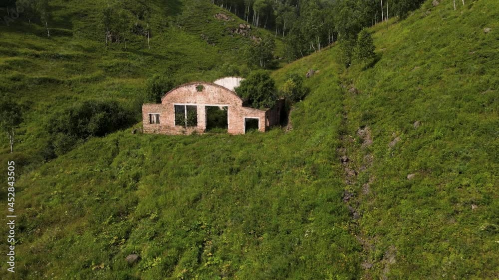 4K Flying over an abandoned, destroyed building in a mountain gorge with green grass and trees. The ruins of a house without a roof and windows. 4K Flying over an abandoned, destroyed building in a mountain gorge with green grass and trees. The ruins of a house without a roof and windows.