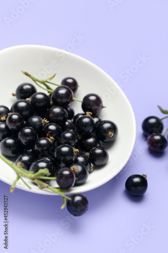 Plate with ripe black currant on color background, closeup