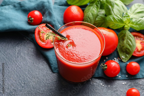 Glass of tasty tomato juice on dark background