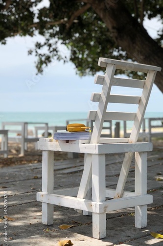 Relax time on the beach sit on the white chair with music speaker and pocket book concept for tourism