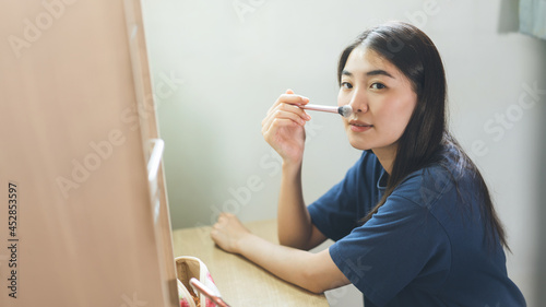 Portrait of single stills wellness young adult asian woman makeup before mirror at home photo