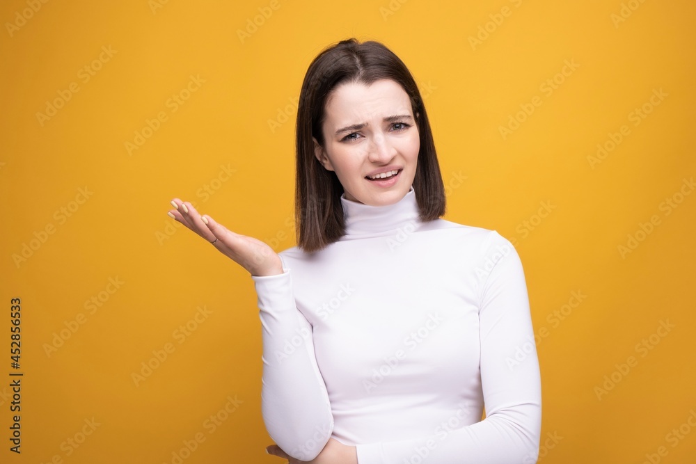Obraz premium Close-up portrait of a surprised brunette on a yellow background