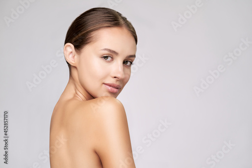 Beautiful Young Woman with Clean Fresh Skin standing over light grey background