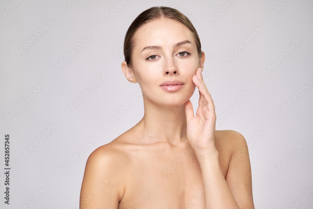 Beautiful Young Woman with Clean Fresh Skin standing over light grey background Beautiful Young Woman with Clean Fresh Skin standing over light grey background
