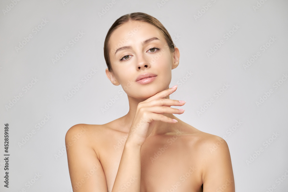 Beautiful Young Woman with Clean Fresh Skin standing over light grey background Beautiful Young Woman with Clean Fresh Skin standing over light grey background