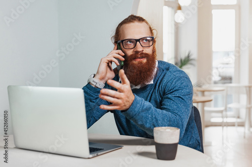 Redhead man working and talking on the phone in a cafe