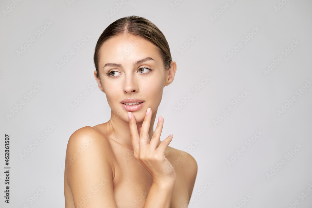 Beautiful Young Woman with Clean Fresh Skin standing over light grey background Beautiful Young Woman with Clean Fresh Skin standing over light grey background