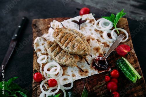 Lula kebab on pita bread with vegetables and sauce close-up photo