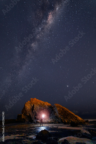 Milkway sky over Currumbin Rock, Gold Coast with person holding light.