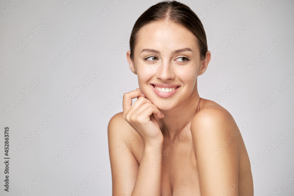Beautiful Young Woman with Clean Fresh Skin standing over light grey background