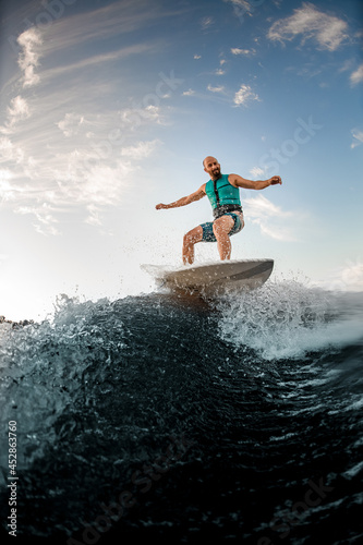 Active adult man balancing on wakesurf board on the splashing wave © fesenko