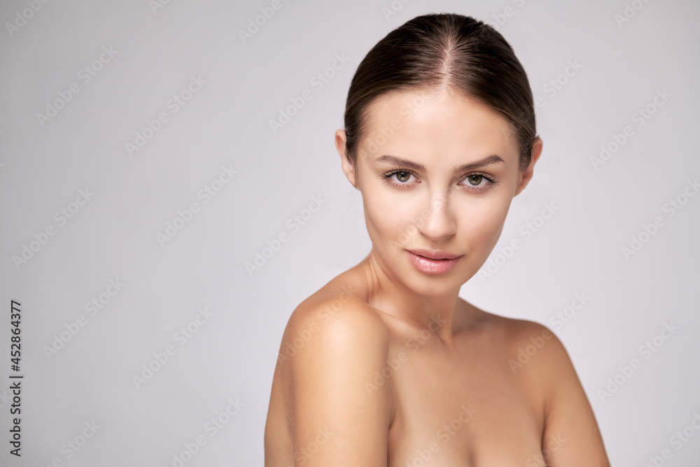 Beautiful Young Woman with Clean Fresh Skin standing over light grey background Beautiful Young Woman with Clean Fresh Skin standing over light grey background