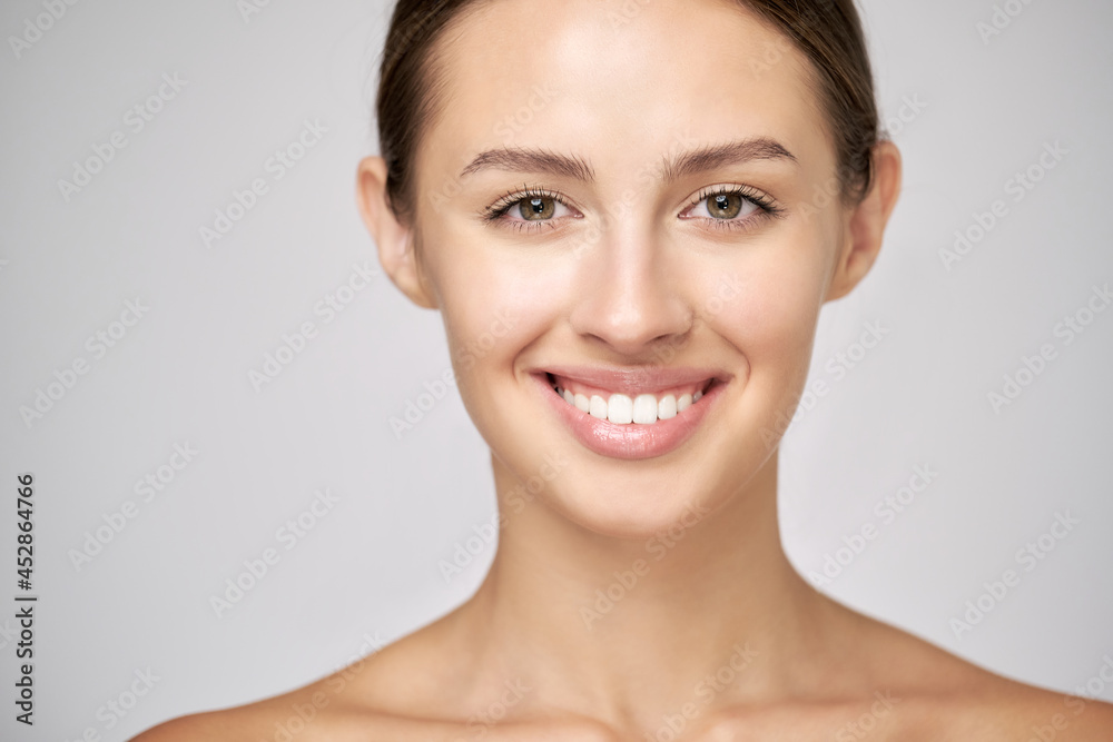 Beautiful Young Woman with Clean Fresh Skin standing over light grey background Beautiful Young Woman with Clean Fresh Skin standing over light grey background