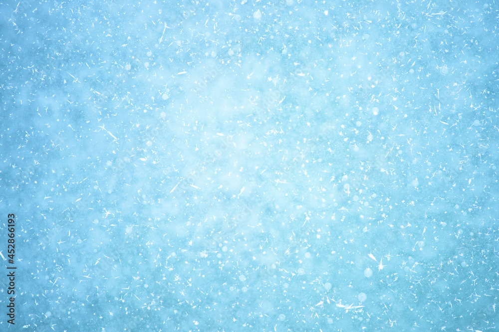 Glowing naturally blue ice with a haze effect with white patches of frost and frozen air bubbles. Background Glowing naturally blue ice with a haze effect with white patches of frost and frozen air bubbles. Background