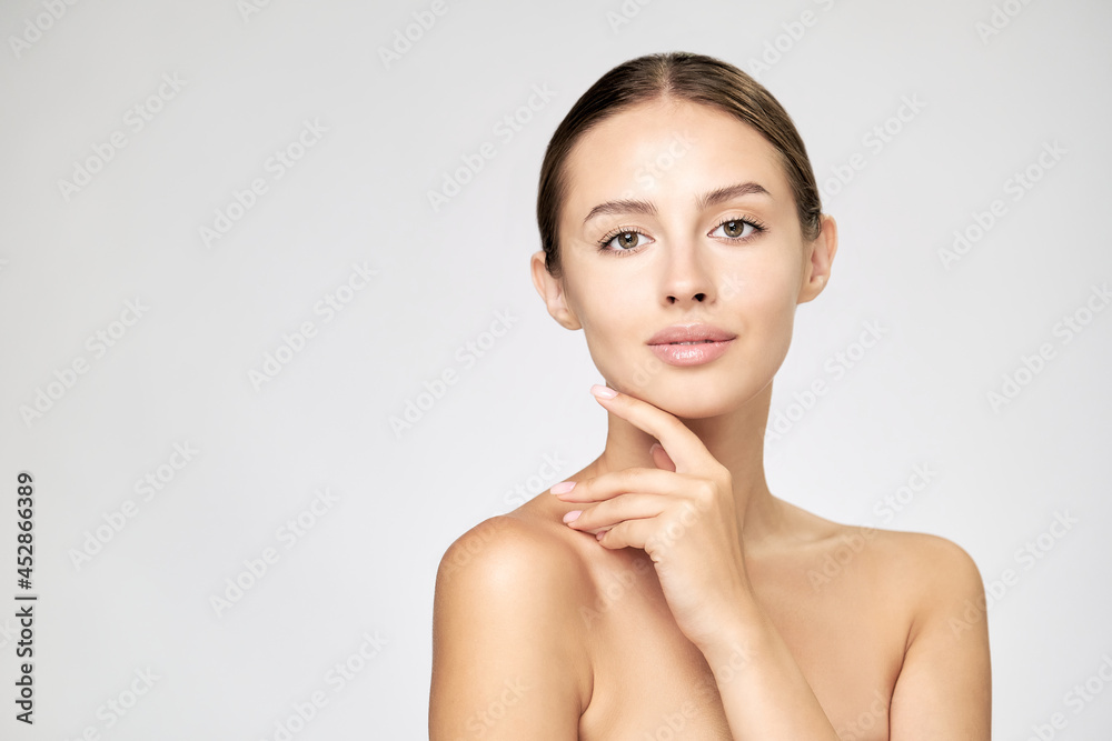 Beautiful Young Woman with Clean Fresh Skin standing over light grey background Beautiful Young Woman with Clean Fresh Skin standing over light grey background