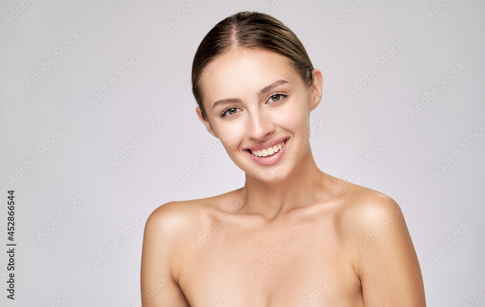 Beautiful Young Woman with Clean Fresh Skin standing over light grey background