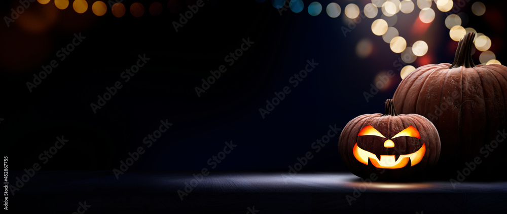 Two halloween lanterns with evil eyes and face on a wood table with a spooky dark blue background at night with light bokeh. - obrazy, fototapety, plakaty 