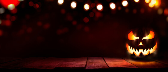 A scary halloween lantern with evil eyes and face on a rustic wood table with a spooky red background.