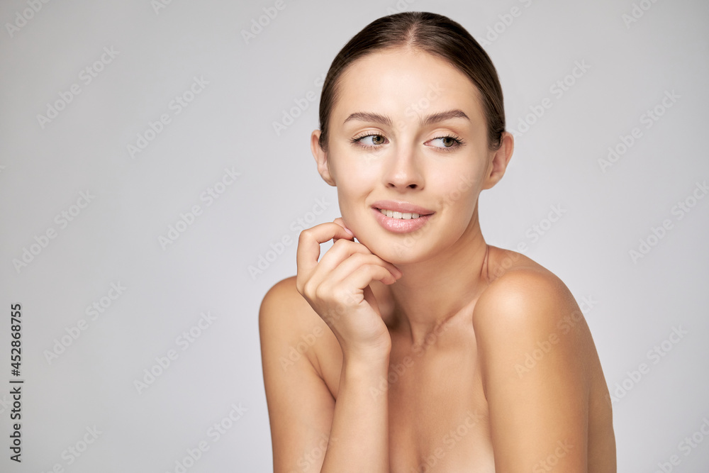 Beautiful Young Woman with Clean Fresh Skin standing over light grey background Beautiful Young Woman with Clean Fresh Skin standing over light grey background