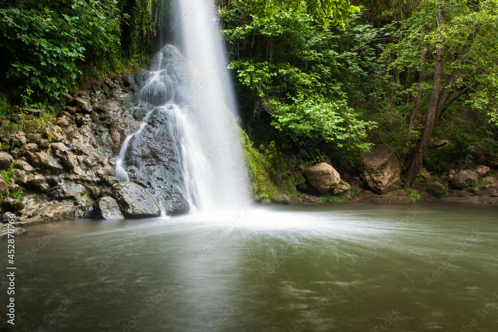 Una cascada cae sobre unas rocas y un lago en medio del bosque en una foto de larga exposición Una cascada cae sobre unas rocas y un lago en medio del bosque en una foto de larga exposición