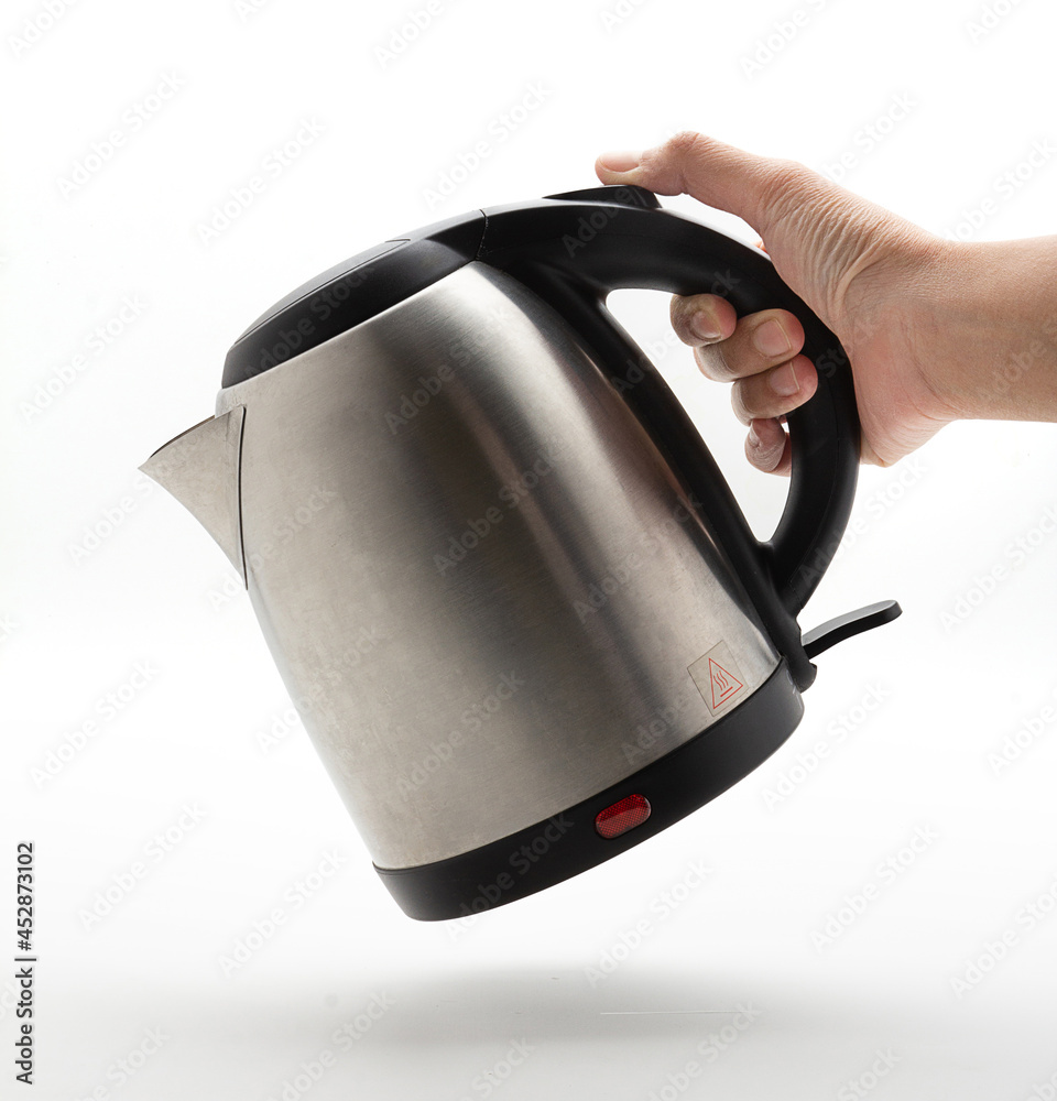 Hand holding the kettle at tilted angle like it's pouring water. Silver Electric Kettle on a white background, Water Kettle, Fast Heating. Modern technology brewing. Hand holding the kettle at tilted angle like it's pouring water. Silver Electric Kettle on a white background, Water Kettle, Fast Heating. Modern technology brewing.