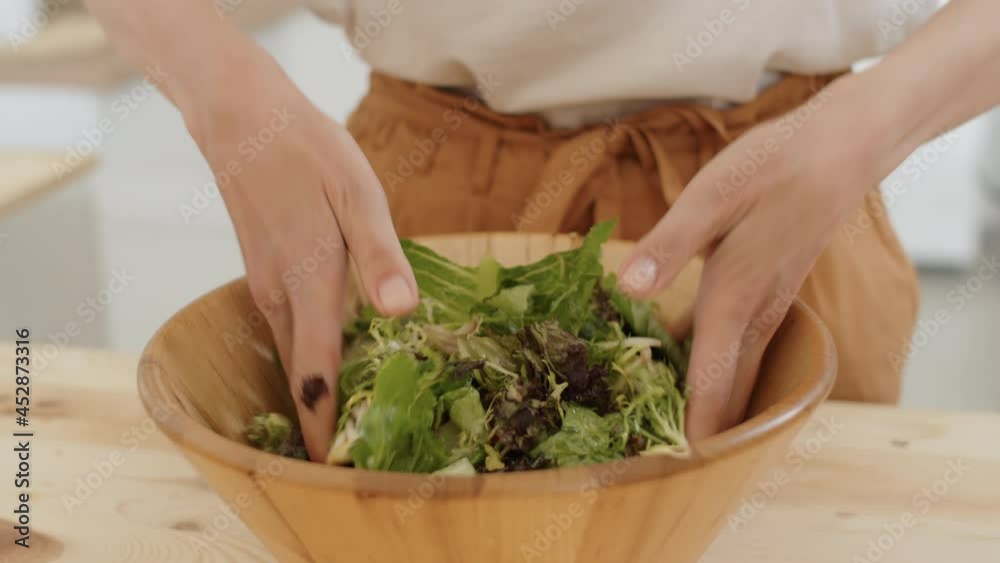 Close up shot of hands of unrecognizable woman mixing vegetable salad in wooden bowl Close up shot of hands of unrecognizable woman mixing vegetable salad in wooden bowl