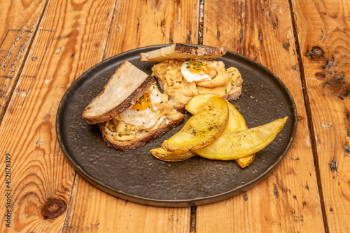 Delicious poulard stew sandwich with fried quail eggs and roasted potato wedges photo