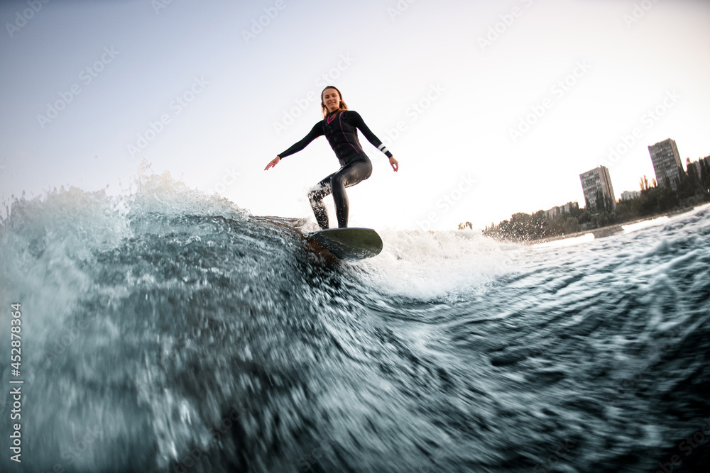 active female wakesurfer balanced on the board on river wave