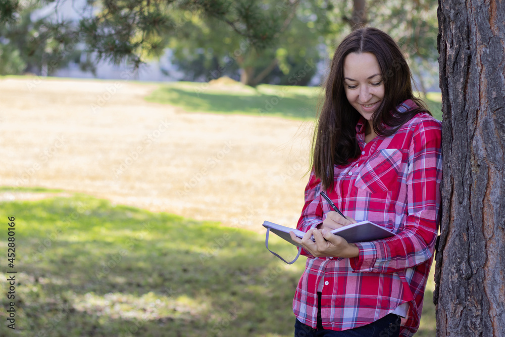 Fototapeta premium a woman stands near a tree and writes
