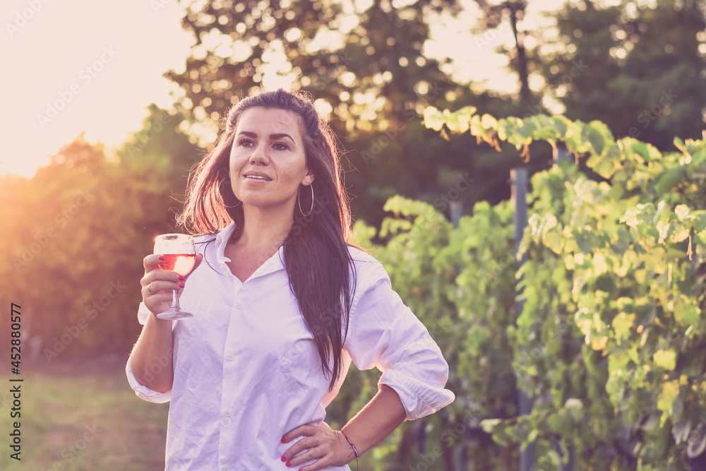 Young beautiful smiling woman sitting with a cat in a Vineyard with a glass of rose wine. Woman playing with cat during the summer vacation Young beautiful smiling woman sitting with a cat in a Vineyard with a glass of rose wine. Woman playing with cat during the summer vacation