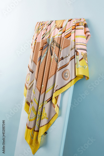 Subject photo of bright scarf with colorful fashion design. Stylish silk headkerchief is hanging on the white board.   photo