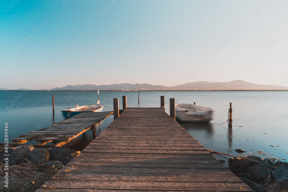 Fototapeta premium Long exposure view of a little pier and little fisherman's boats at Giliacquas park at sunset