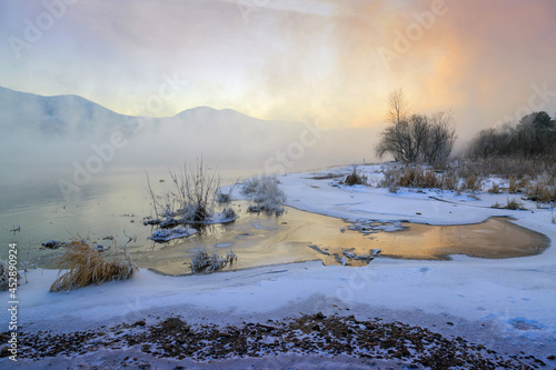 Winter landscape with river, ice banks and mountains in the background © Marina