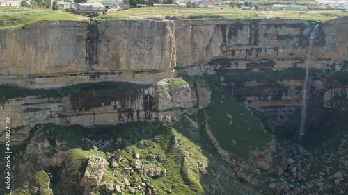 High waterfall flowing among the stone walls of a deep canyon. Republic of Dagestan, Russia. The concept of traveling in your country photo