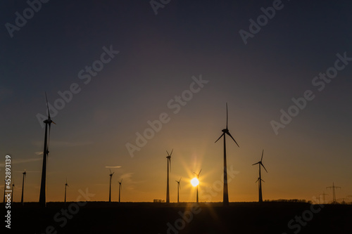 Windräder bei Sonnenuntergang auf einem Feld produzieren Strom 