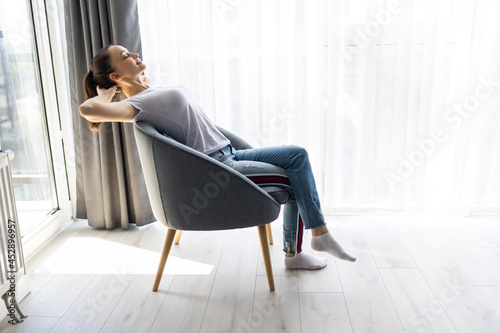 Young woman relaxing in modern chair at home
