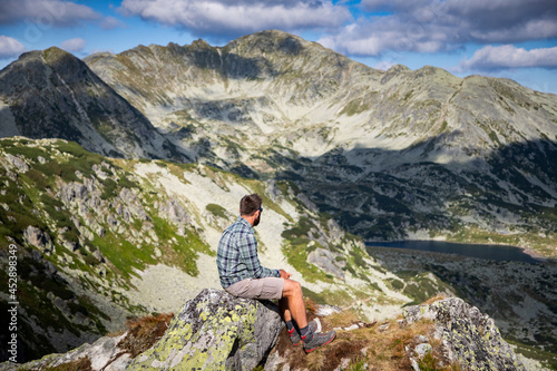 handsome man sitting on mountain top in amazing summer landscape