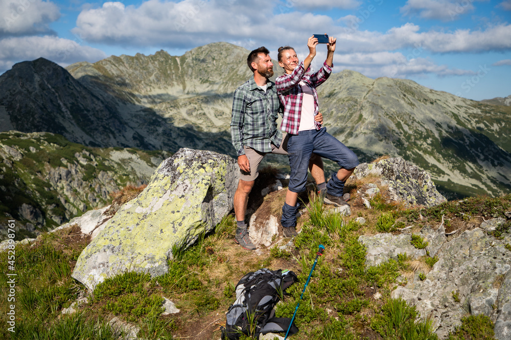 couple taking a selfie on mountain top in amazing summer landscape