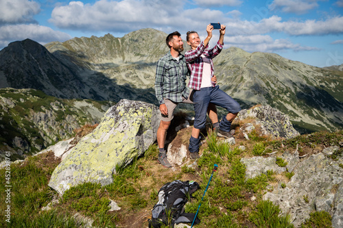 couple taking a selfie on mountain top in amazing summer landscape