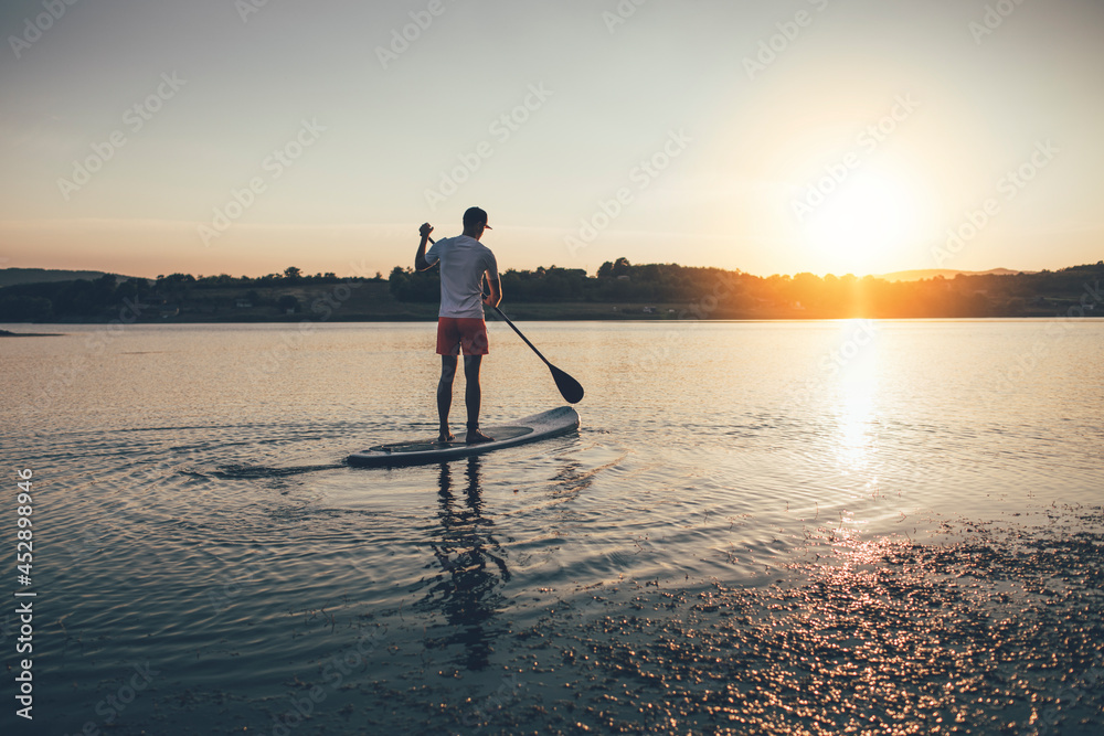 Man floating on the lake on paddle board, copy space