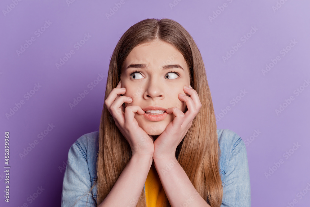 Portrait of worried lady bite nails anxious look empty space wear jeans clothes on purple background Portrait of worried lady bite nails anxious look empty space wear jeans clothes on purple background
