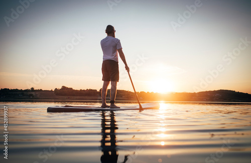 Rear view of man paddling board at sunset © yossarian6
