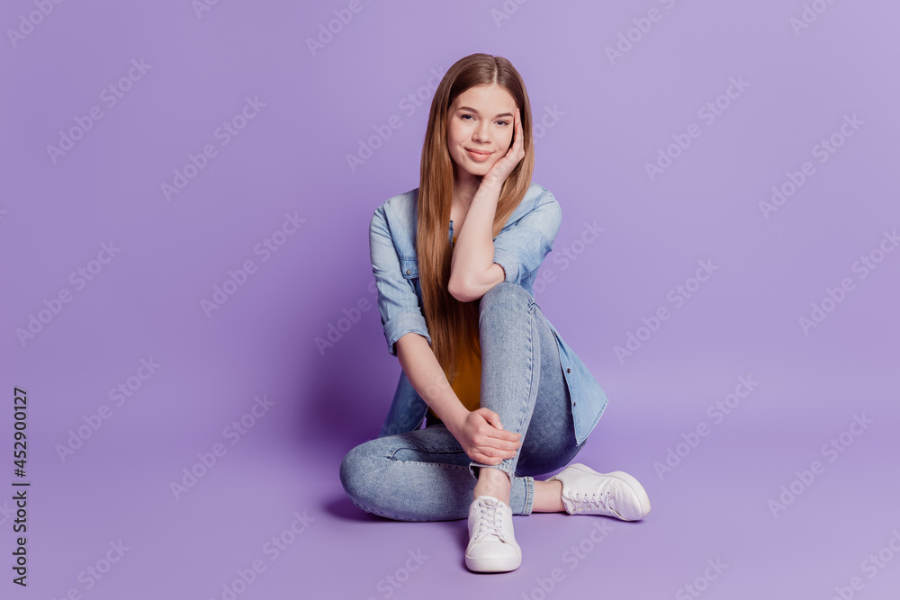 Photo of charming girl sit floor hands legs on purple background Photo of charming girl sit floor hands legs on purple background