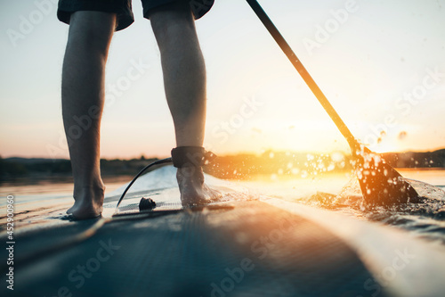 Картината върху платно Close up of man paddleboarding at sunset