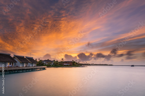 Sunset over sand island beach in Maldives. Crossroads Maldives islands. Long exposure picture taken in july 2021