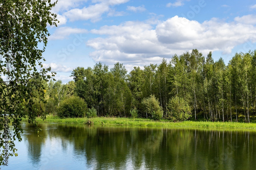 Landscape over the water surface, green trees around the dam. The magnificent nature of Siberia