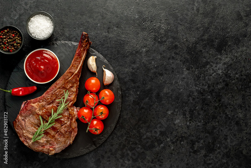 grilled Tomahawk steak with spices on a stone background with copy space for your text