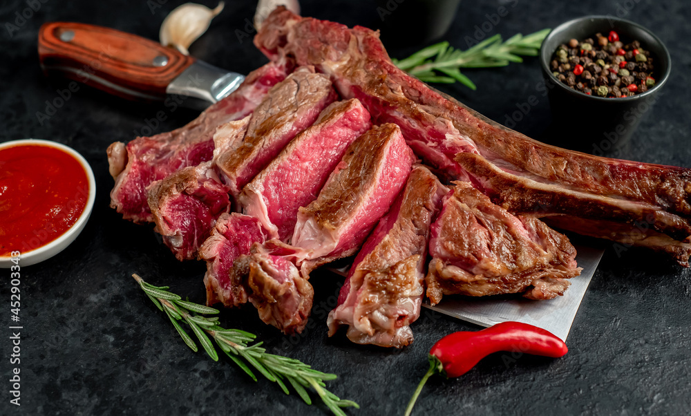 grilled Tomahawk steak, on a knife with spices on a stone background grilled Tomahawk steak, on a knife with spices on a stone background