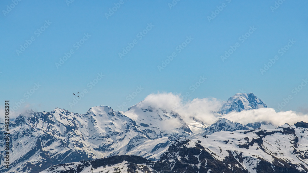 Misty snow covered mountain peaks of south island New Zealand with a small flock of birds