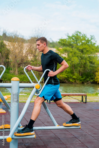 Strong young muscular man doing walking exercise at the outdoors gym © qunica.com